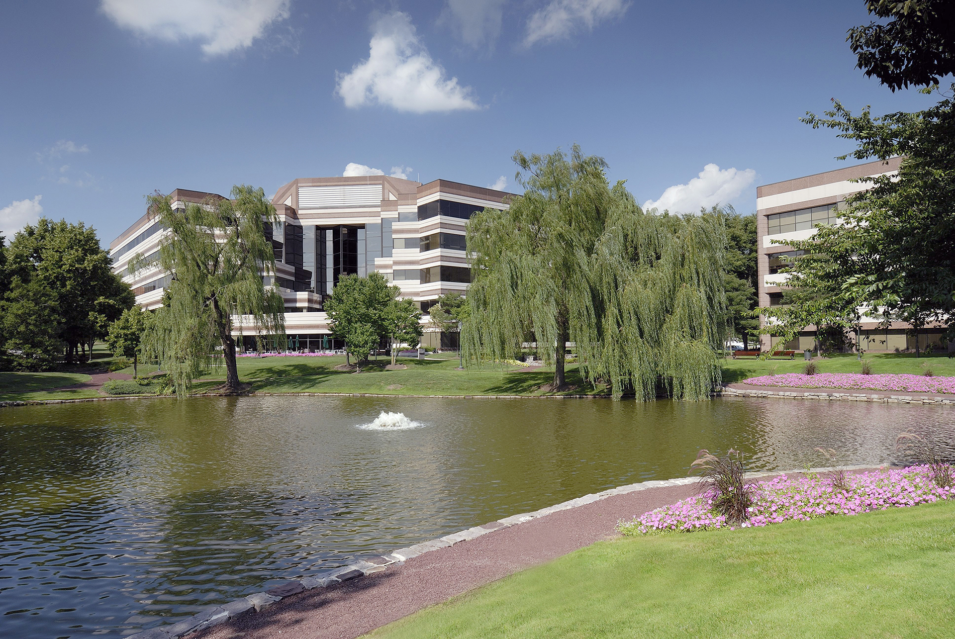 Exterior shot of an office building overlooking a pond and walking path.