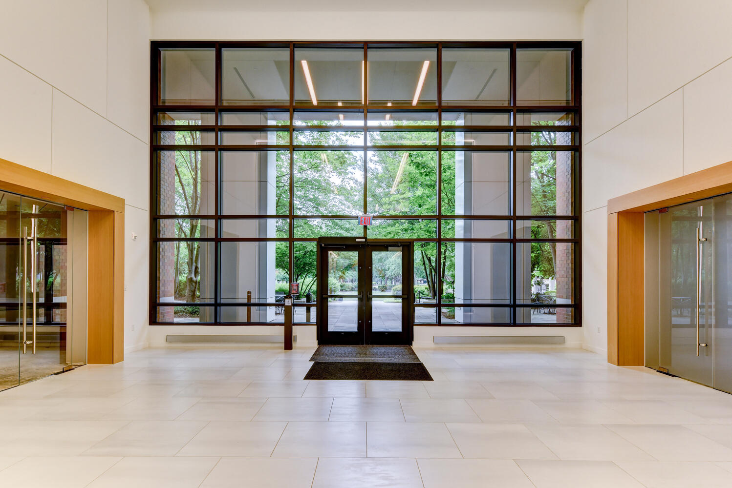 Interior of an office building lobby showing floor to ceiling windows and door.