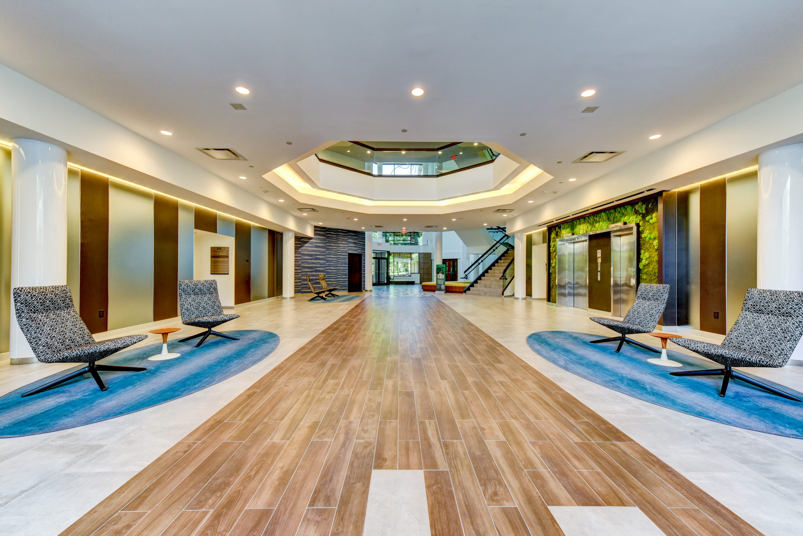 Interior lobby of an office building, featuring seating areas and pops of wood and blue design elements.