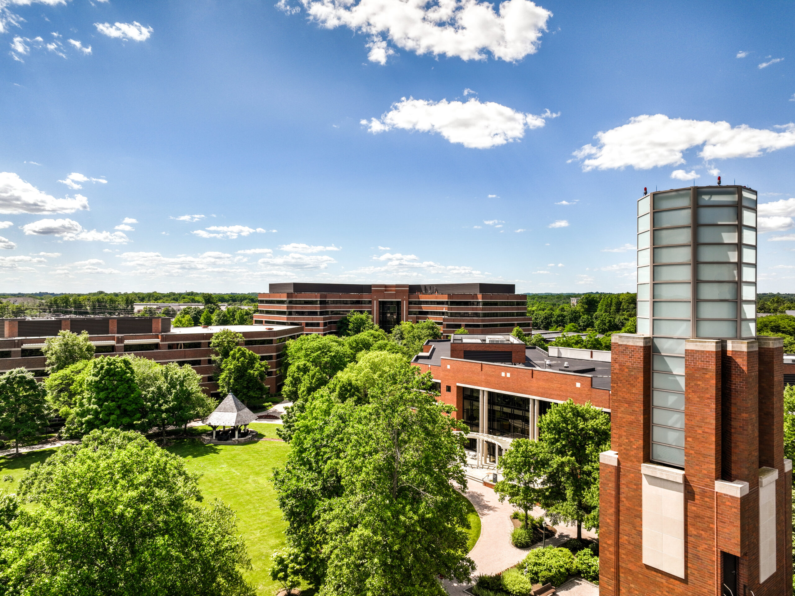 Overview of a group of office buildings located at Carnegie Center, featuring an open grass area under a bright blue sky.